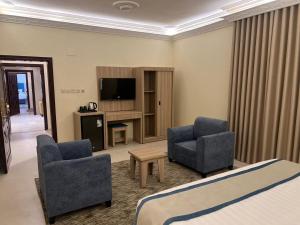 a hotel room with a bed and two chairs and a television at أجنحة أحد للشقق المفروشة in Al Madinah +15 photos