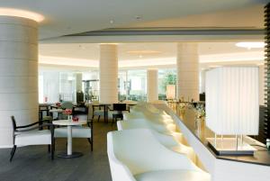 a lobby with white couches and chairs and tables at Starhotels Grand Milan in Saronno