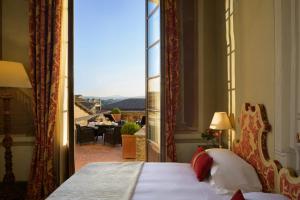 a bedroom with a bed and a view of a balcony at Grand Hotel Continental Siena - Starhotels Collezione in Siena