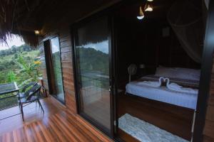 a room with a bed and a sliding glass door at Mae Buya Coffee Farm Stay in Ban Huai Pong Nam Ron