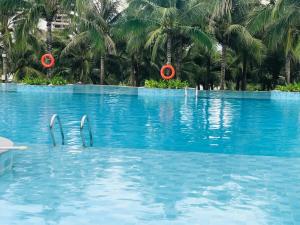 a swimming pool with palm trees in the background at Cam Ranh Resort in Cam Ranh