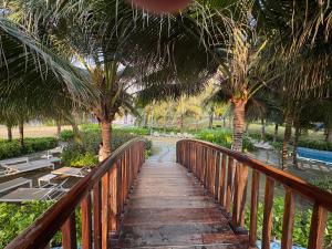 a wooden walkway with palm trees and a bridge at Cam Ranh Resort in Cam Ranh