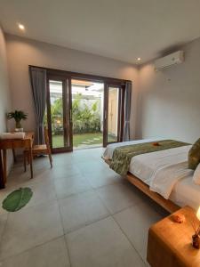 a bedroom with a bed and a table and a window at Casagana by Gana Management Canggu in Dalung