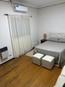 a bedroom with a bed and two white stools at Ideal Centro Junin in Junín