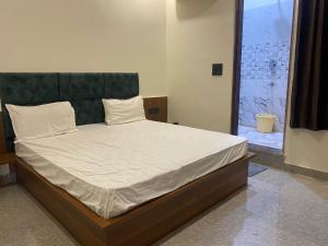 a bedroom with a large bed with white sheets at Hotel O Riwaz Inn in Gwalior