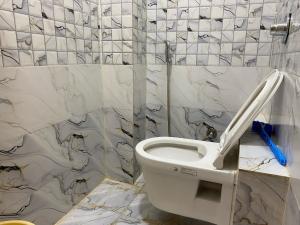 a bathroom with a toilet in a tiled wall at Hotel O Riwaz Inn in Gwalior