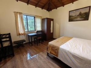 a bedroom with a bed and a desk and a table at Watawala Tea Garden in Rozella