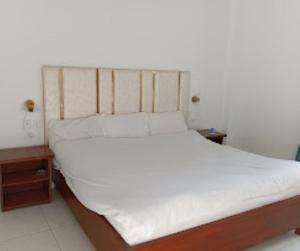 a bedroom with a bed with white sheets and two tables at Kings Inn Hotel in Dargai