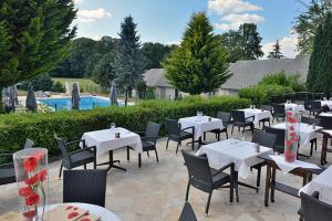 een restaurant met witte tafels en stoelen en een zwembad bij Hôtel Restaurant Les Coquelicots, The Originals Relais (Inter-Hotel) in Saint-Pardoux-lʼOrtigier