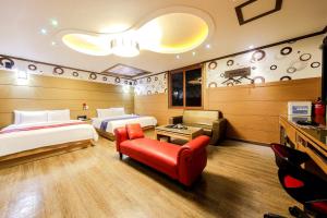 a hotel room with two beds and a red couch at Yeosu Apple Hotel in Musŏn