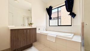 a bathroom with a tub and a sink and a window at Highlands 3B House by GoodLive in Craigieburn +44 photos