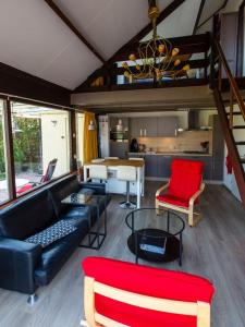 a living room with a black couch and a red chair at Vakantiehuis in Stavenisse