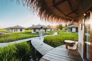 a man walking on a wooden walkway outside a house at Na Bua Villa Chiangrai in Ban Rim Lao