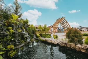 a man walking on a bridge over a pond with a waterfall at Na Bua Villa Chiangrai in Ban Rim Lao +12 photos