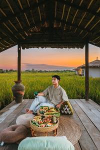 a man sitting on a table with a bowl of food at Na Bua Villa Chiangrai in Ban Rim Lao
