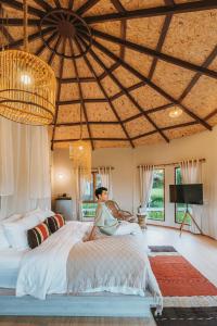 a woman sitting on a bed in a bedroom at Na Bua Villa Chiangrai in Ban Rim Lao