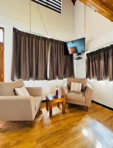een woonkamer met twee banken en een tv bij Queens Lake Cabin in Nuwara Eliya