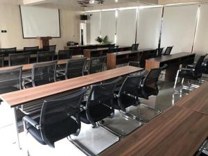 a classroom with wooden tables and black chairs at UP and IN Hotel Jiangsu Xuzhou Gulou District Lvdizhichuang in Xuzhou