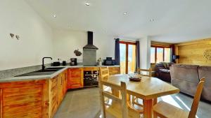 a kitchen and living room with a table and a stove at CASA-Mezan appartement cosy 2 chambres in Aiguilles
