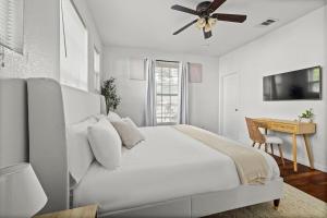 a white bedroom with a bed and a ceiling fan at Central East Austin Luxury Hot Tub & Game Room in Austin