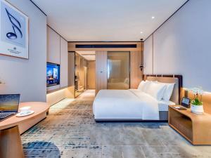 a bedroom with a large white bed and a desk at Mousse Hotel Liyang Railway Station Museum Branch 