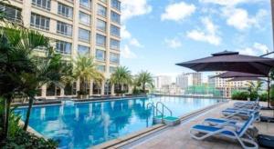 a swimming pool with chairs and an umbrella and a building at Ming Guan Hotel in Sihanoukville