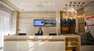 Eine Frau, die an einem Tresen in einer Lobby sitzt. in der Unterkunft City Comfort Inn Fuyang Hongqi Middle School Erlijing Night Market in Fuyang + 66 Fotos