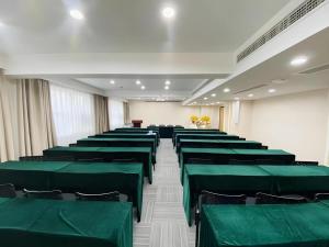 a conference room with green chairs and a podium at GreenTree Inn Luoyang Railway Station Wangfujing Wangcheng Park in Luoyang