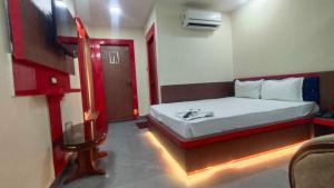 a small room with a bed and a television at Collection O A&M Regency, WEBLE More in Thākurdwari