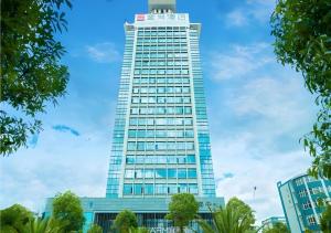 een hoog gebouw met een blauwe lucht op de achtergrond bij Echarm Hotel Qujing High-speed Railway Station 1st Wuguan Center in Qujing