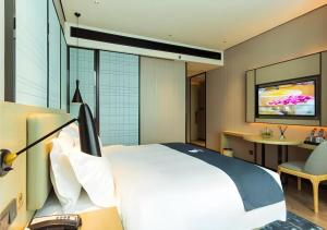 een hotelkamer met een bed en een televisie bij Echarm Hotel Qujing High-speed Railway Station 1st Wuguan Center in Qujing