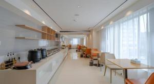 a large kitchen with tables and chairs in a room at City Comfort Inn Hefei 1912 Ganghui Plaza in Hefei