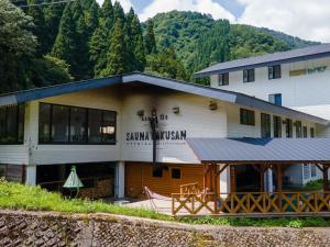 白山市千丈温泉 ペンシオーネセイモア サウナはくさん SENJO Onsen PENSIONE SEYMOUR Sauna Hakusan的以山为背景的建筑物