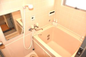 ein Badezimmer mit einer weißen Badewanne und einem Spiegel in der Unterkunft cotomaro 305 -Apartment Stay Near Matsumoto Castle- in Matsumoto