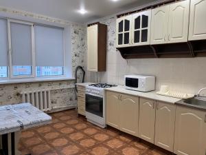 a kitchen with white cabinets and a stove top oven at Хромтау in Khromtaū
