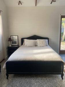 a bedroom with a bed with a black headboard and a television at Mini Mullum Studio Retreat in Mullumbimby