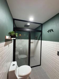 a bathroom with a toilet and a glass shower at Hotel ënxë habitación grande camas queen in Cuetzalán del Progreso
