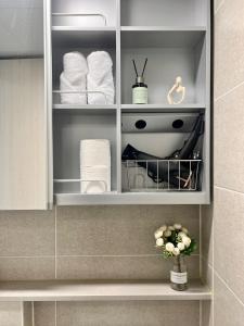 ein Badezimmerschrank mit Handtüchern und einer Blumenvase in der Unterkunft 송도 한라웨스턴파크, 레지던스형 숙소 in Taeam