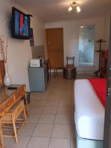 ein Wohnzimmer mit einem Sofa und einem Fernseher an der Wand in der Unterkunft Neo & Ruks Guest Houses Boston Belleville 8 in Bellville