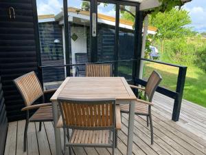 een houten tafel en stoelen op een terras bij Cozy Beach House In The First Row in Karrebæksminde +31 foto's