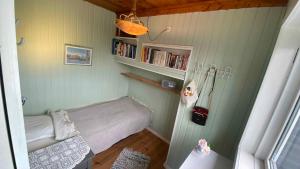 een kleine slaapkamer met een bed en een boekenplank bij Cozy Beach House In The First Row in Karrebæksminde