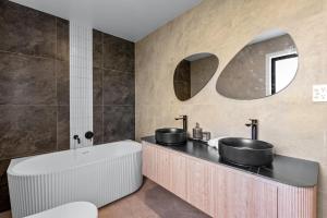 a bathroom with two sinks and a bath tub at Its a bit country and a bit town in Karaka +32 photos