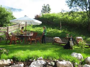 um grupo de pessoas sentadas à volta de uma mesa com um cão em DEVA Hotel Alpenglück em Weißbach