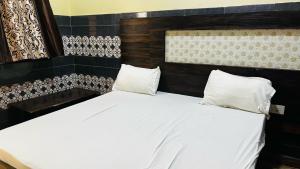 a bed with white sheets and pillows in a room at Hotel O Mathura Janam Bhumi Link Road in Bhuteshwar +9 photos