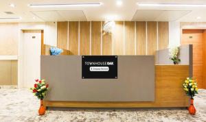 a lobby with a counter with flowers inront of it at Townhouse Oak CSJMU Kanpur Formerly Shree Dev Villa in Kaliānpur