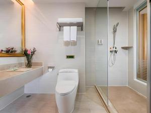 a white bathroom with a toilet and a shower at Vienna Hotel Shenzhen Pingdi Huancheng South Road in Longgang