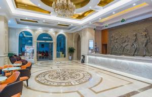 een lobby met een kroonluchter en een muur met een sculptuur bij Vienna Hotel Hubei Enshi Railway Station in Longfengba