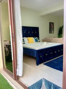 a bedroom with a bed with a blue headboard at Spacious Calitwapa Studio Apartment with AC and Private cook upon request available in Mtwapa