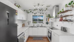 une cuisine blanche avec des armoires blanches et une fenêtre dans l'établissement The Infinite Pi Escape, à Bongaree