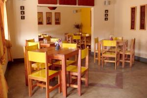 ein Esszimmer mit Holztischen und gelben Stühlen in der Unterkunft Dutchess Hotel and Restaurant in Fort Portal